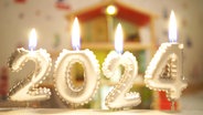 Brennende Kerzen in Zahlenform bilden die Zahl 2024. © Screenshot 