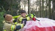 Junge Helferinnen der freiwilligen Feuerwehr befüllen einen mobilen Deich mit Wasser. © Screenshot 