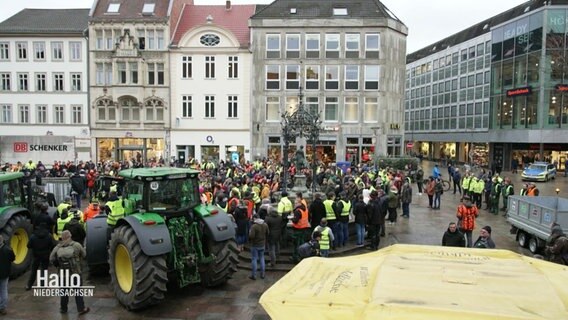 Szene bei einer Protestdemo: Eine Menschenansammlung auf einem zentralen Platz in eienr Stadt, zwei Traktoren sind in der Innenstadt geparkt. © Screenshot 