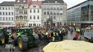 Szene bei einer Protestdemo: Eine Menschenansammlung auf einem zentralen Platz in eienr Stadt, zwei Traktoren sind in der Innenstadt geparkt. © Screenshot 