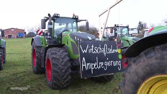 Ein großer Traktor ist für eine Demonstration vorbereitet: Am Trecker prangen ein Schild mit der Aufschrift "Wirtschaftselend Ampelregierung", eine auf Karton gemalte Ampel und ein Galgenstrick. © Screenshot 