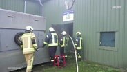 Feuerwehrleute bringen Schweine bei einem Brand aus einem Stall. (Archivbild) © Screenshot 