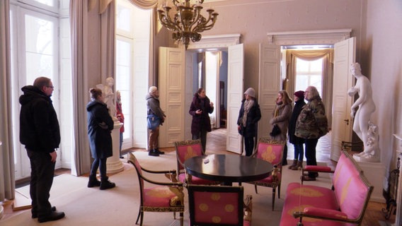 Besucher stehen im Halbkreis in einem Raum. © Screenshot 