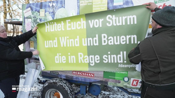 Eine Frau und ein Mann halten ein Plakat mit der Aufschrift "Hütet euch vor Sturm und Wind und Bauern, die in Rage sind!" © Screenshot 