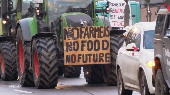 Eine Traktor-Kolonne fährt mit Plakaten versehen durch eine Stadt. © Screenshot 