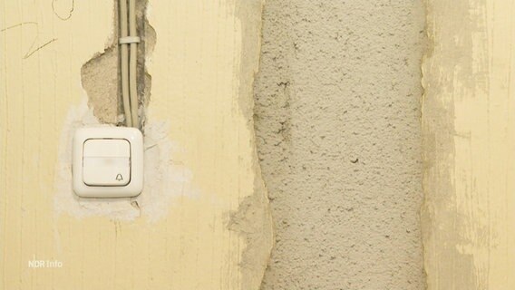 Ein unverputze Wand mit offenen Kabeln in einem Hausflur. © Screenshot 
