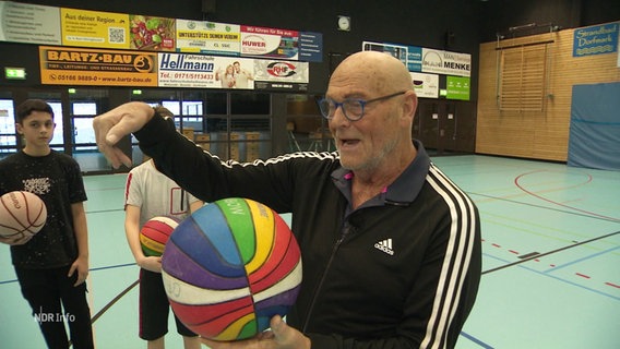 Manfred Lüssenhop mit Basketball in der Hand. © Screenshot 