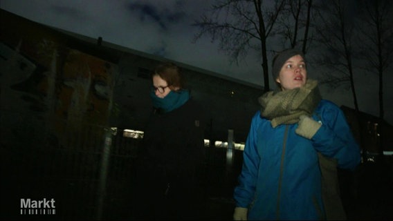 Zwei Personen gehen nebeneinander durch eine dunkle Straße. © Screenshot 