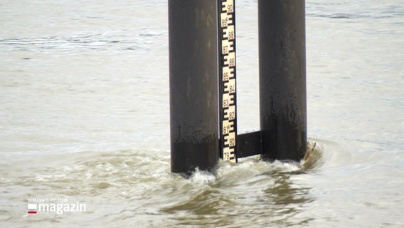 Ein Messpegel zeigt den Wasserstand eines Flußes. © Screenshot 