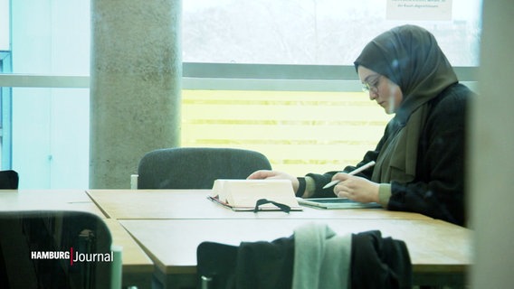 Eine junge Frau mit Kopftuch sitzt an einem Tisch. © Screenshot 