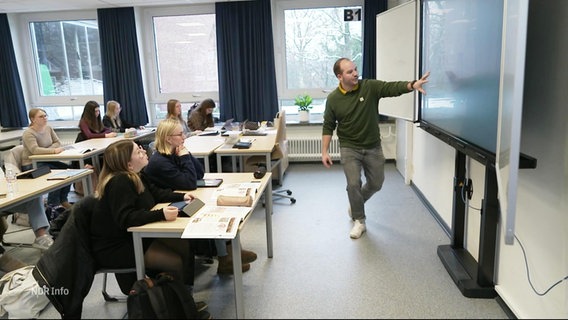 Ein Lehrer und Schülerinnenin in einem Klasseraum. © Screenshot 