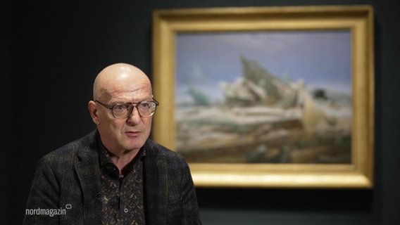 Komponist Christian Jost sitzt vor dem Gemälde "das Eismeer" von Caspar David Friedrich. © Screenshot 