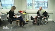 Zwei Personen in einem Raum. Eine sitzt im Rollstuhl. © Screenshot 