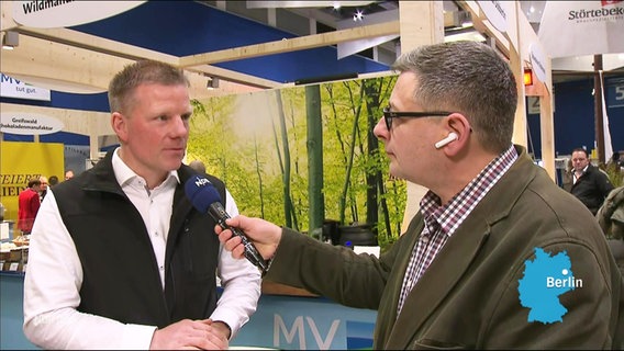 Reporter Frank Breuner spricht mit einem Landwirt auf der Grünen Woche. © Screenshot 