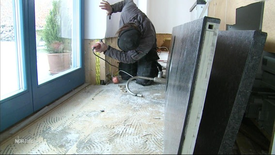 Eine Person bei Renovierungsarbeiten in einem Erdgeschoss. © Screenshot 