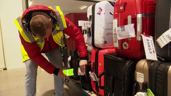 Ein Mitarbeiter der Gepäckservice-Firma Tefra scannt die Etiketten von Koffern. © Screenshot 