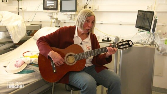 Anne von Hartmann, bekannt als Schwester Anne, spielt Gitarre auf der Kinderherzstation. © Screenshot 