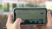 Ein Handy wird mit zwei Händen gehalten. © Screenshot 