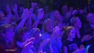 Klatschende Menschen in farbigem Licht. © Screenshot 