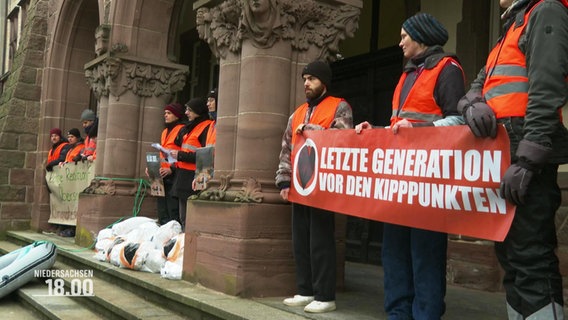 Mehrere Mitglieder der "Letzten Generation" protestieren vor einem Gerichtsgebäude gegen einen Prozess. © Screenshot 