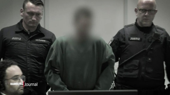 Eine Person mit geblurrtem Gesicht wird von zwei Justizbeamten in ein Gerichtssaal geführt. © Screenshot 