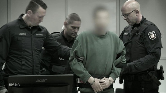 Eine Person mit geblurrtem Gesicht wird von Justizbeamten in ein Gerichtssaal geführt. © Screenshot 