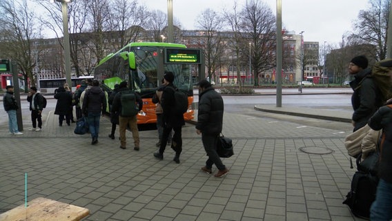 Reisende stehen vor einem Fernbus des Anbieters Flixbus am Busbahnhof in Hamburg Schlange. © Screenshot 