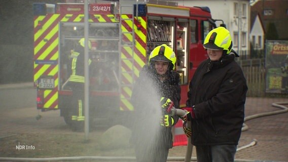 Zwei Menschen, die einen Feuerwehrschlauch benutzen. © Screenshot 