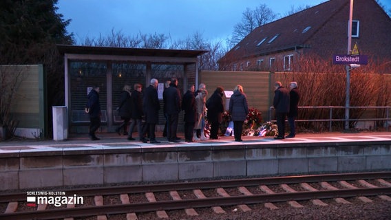 Menschen stehen trauernd am Brokstedter Bahnhof. © Screenshot 