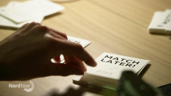 Eine Hand greift nach einer weißen Karte, auf der in schwarzen Blockbuchstaben steht: "Match later". © Screenshot 