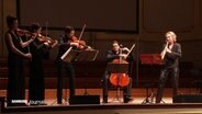 Drei Geigerinnen und Geiger, ein Cellist und eine Sopransaxophonistin auf der Bühne der Laeiszhalle. © Screenshot 