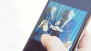 Eine Hand hält ein Smarthpone, auf dessen Display ein Bild zu sehen ist, wie der Kreisverband Northeim der AfD einen parteiinternen Preis an den AfD-Politiker Björn Höcke verleiht. © Screenshot 