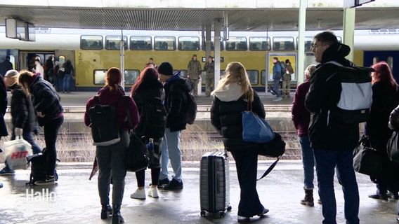 Wartende Reisende auf einem Bahnsteig. © Screenshot 