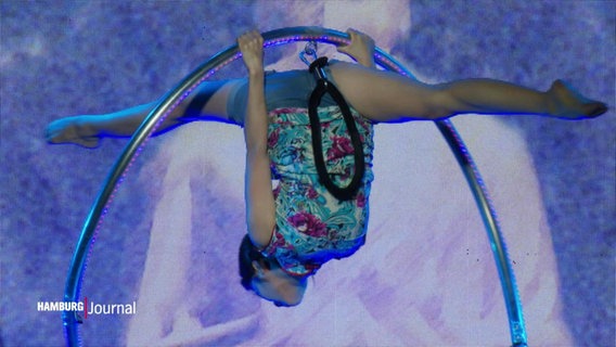 Eine Akrobatin hängt in einem Ring © Screenshot 