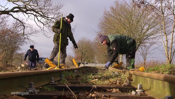 Mehrere Männer reparieren die Gleise einer Schmalspurbahn. © Screenshot 