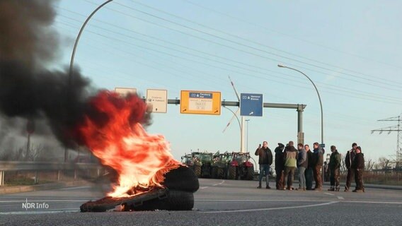 Reifen Brennen auf einer Autobahn-Zufahrt. Im Hintergrund sind mehrere Traktoren zu sehen. © Screenshot 