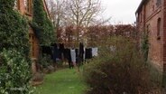 In einem Garten hängt Wäsche auf der Leine. © Screenshot 