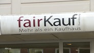 Ein Schild mit der Aufschrift "fairKauf - Mehr als ein Kaufhaus" über dem Eingang eines Sozialkaufhauses. © Screenshot 