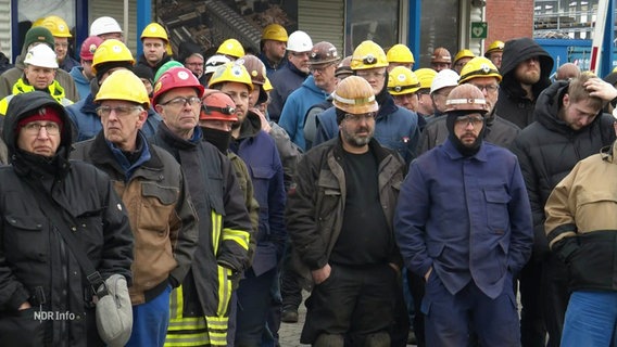 Arbeitende der Werft Nobiskrug mit gelben Arbeitshelmen und in Arbeitskleidung bei einer Kundgebung. © Screenshot 