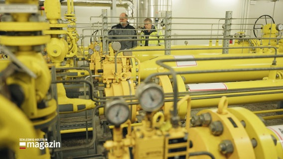 Eine Wasserstoffanlage: Überall verlaufen gelb gestrichenene Rohre und Ventile; im Hintergrund zwei Personen. © Screenshot 