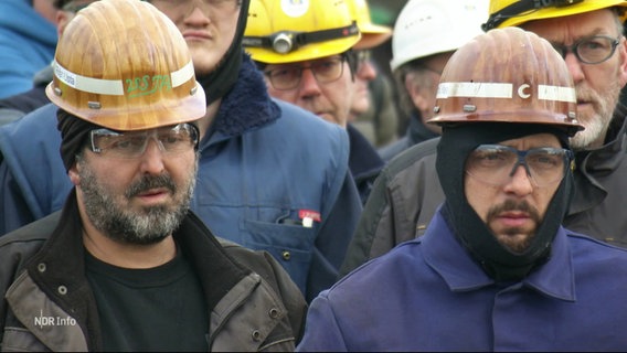 Menschen mit Helmen und Schutzbrillen stehen Seite an Seite. © Screenshot 