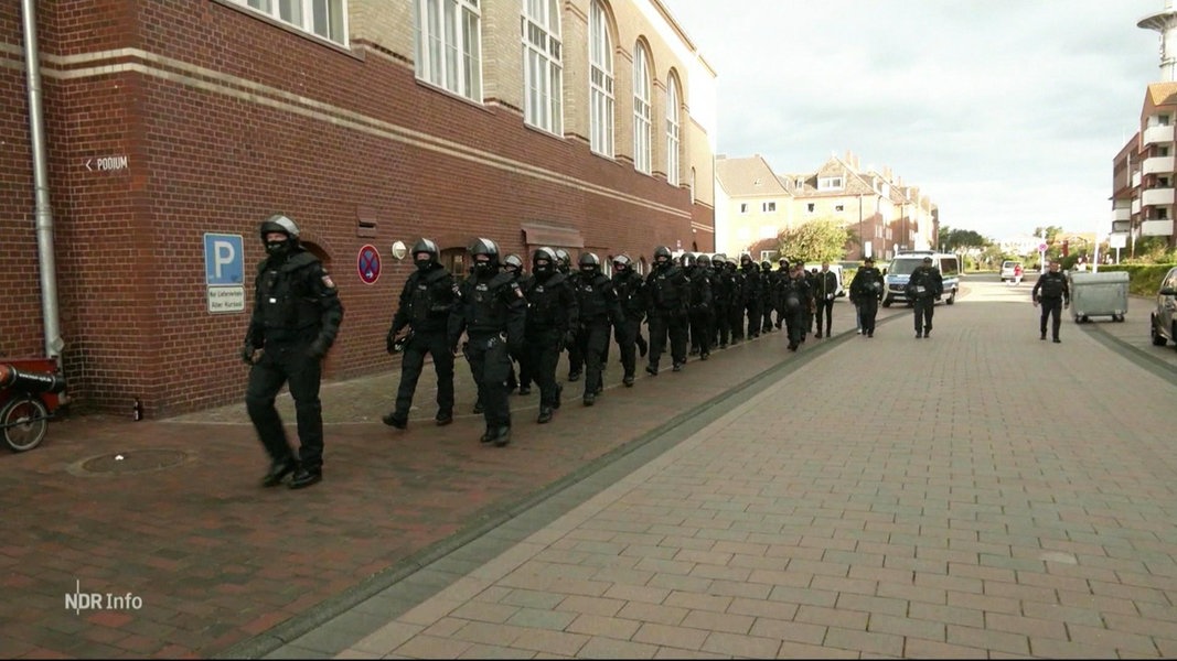 Eine Gruppe uniformierter Polizisten läuft auf einem Bürgersteig.
