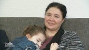 Eine Frau mit schlafenden Kind auf ihrem Arm. © Screenshot 