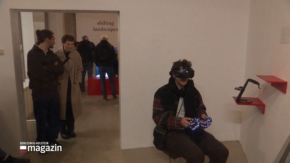 Ein Besucher der Ausstellung sitzt mit einer VR-Brille auf einem Stuhl. © Screenshot 