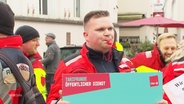 Ein Mann mit Trillerpfeife demonstriert für bessere Arbeitsbedinngungen. © Screenshot 