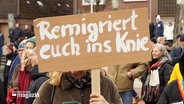 Ein Protestschild mit der Aufschrift: Remigriert euch ins Knie. © Screenshot 