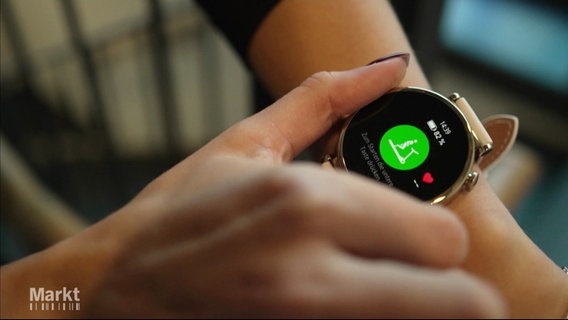 Eine Frauenhand umfasst eine Smartwatch an ihrem Handgelenk. © Screenshot 