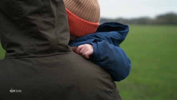 Ein Mann trägt seinen Sohn auf dem Arm. © Screenshot 