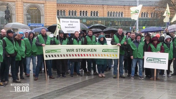 Mitglieder einer Gewerkschaft stehen vor einem Bahnhof. © Screenshot 