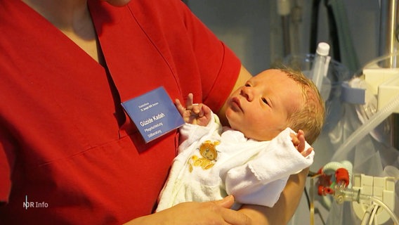 Ein Neugeborenes liegt auf dem Arm einer Pflegerin. © Screenshot 